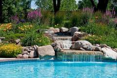 Beautifully landscaped backyard pool with a waterfall.